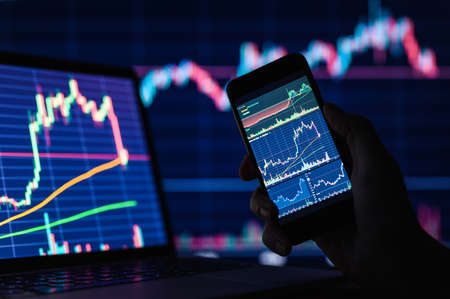 Financial charts on smartphone display and computer monitors. investment concept. selective narrow focus.の写真素材