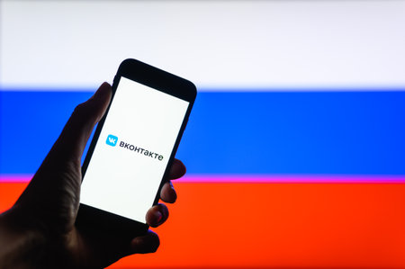 Vladimir, Russia - April 2022: VKontakte social network application on the background of the Russian flag. Selective focus on the logo.のeditorial素材