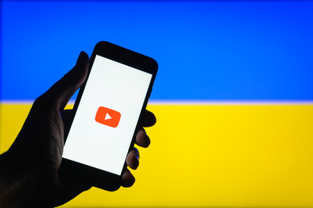 Vladimir, Russia - April 2022: YouTube work in Ukraine. The YouTube app on a smartphone on the background of the Ukrainian flag. Selective focus on logoのeditorial素材