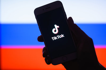 Vladimir, Russia - February 2022: Tik Tok application on a smartphone against the background of the Russian flag. Selective focus on the logo. The concept of using Tik Tok in Russia.のeditorial素材