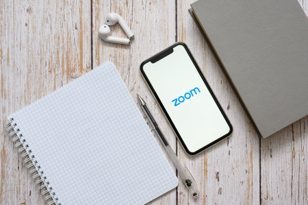 Vladimir, Russia - February 2022: Smartphone on the table with the Zoom application. Online class using the Zoom app on your smartphone.のeditorial素材