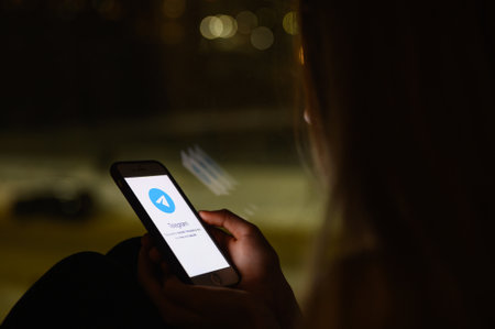 Vladimir, Russia - January 2022: Telegram application on a smartphone in the hands of a girl at night. Selective focus on the logo, narrow focus.のeditorial素材