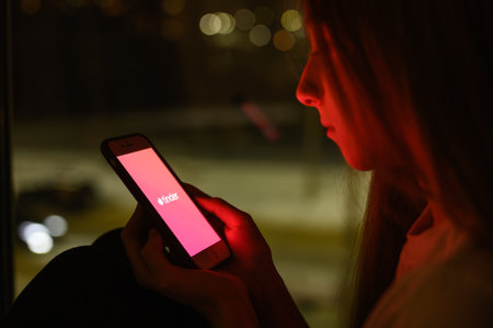 Vladimir, Russia - January 2022: Tinder dating app on a smartphone in the hands of a girl at night. Selective focus on the logo, narrow focus.のeditorial素材