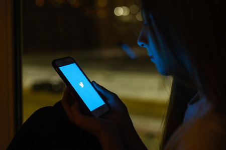 Vladimir, Russia - January 2022: Twitter application on a smartphone in the hands of a teenager. Selective focus on the logo.のeditorial素材