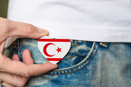Inhabitant of Northern Cyprus. Wooden badge with Turkish Republic of Northern Cyprus flag in the shape of a heart in a man's hand.の写真素材