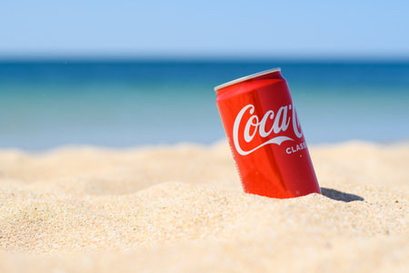 Anapa, Russia-July 2021: An aluminum can of Coca-Cola sits in the sand on a beach during a hot day. In the background the sea.のeditorial素材