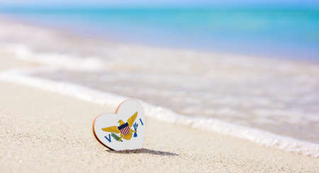 Flag of the US Virgin Islands in the shape of a heart on a sandy beach. The concept of the best vacation in US Virgin Islands resorts.の写真素材