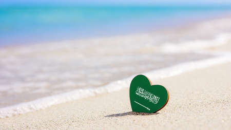Flag of the Saudi Arabia in the shape of a heart on a sandy beach. The concept of the best vacation in Saudi Arabiaの写真素材