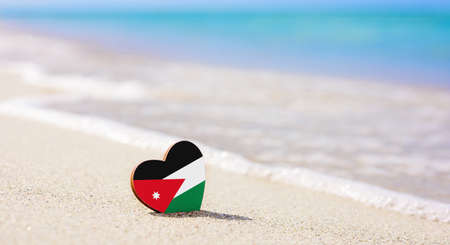 Flag of Jordan in the shape of a heart on a sandy beach. The concept of the best vacation in Jordanの写真素材
