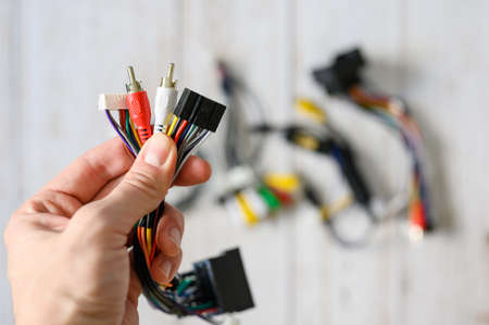 A bundle of wires with different connections in a hand against a background of a pile of various electronic wires. selective focusの写真素材