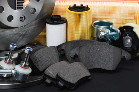 Set of spare parts for car maintenance on a dark background. Selective focus on the brake pads in the center of the frame.の写真素材