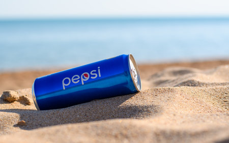 Anapa, Russia - July 2022: Blue can of Pepsi on a sandy beach against the backdrop of the sea.のeditorial素材