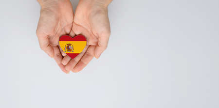 National flag of Spain in the shape of a heart in female hands. Flat lay, copy space.の写真素材