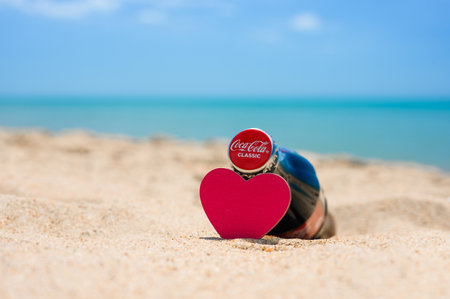 Anapa - Russia, July 2022: A bottle of Coca Cola and a red heart on a sandy beach. Selective focus on bottle cap with logo.のeditorial素材