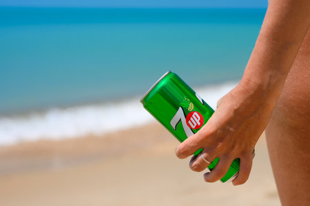 Anapa - Russia, July 2022: Can of non-alcoholic cold drink 7 up in the hand of a girl on the beach. close-up.のeditorial素材