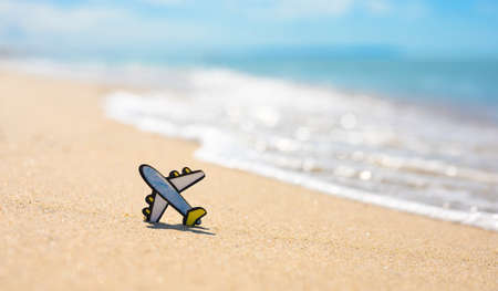 A small figurine of an airplane on a sandy beach against the backdrop of sea waves. Sea travel concept, copy space.の写真素材