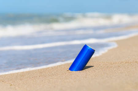 Aluminum can with a cold drink on the sandy seashore against the backdrop of waves. The concept of a relaxing holiday at sea.の写真素材