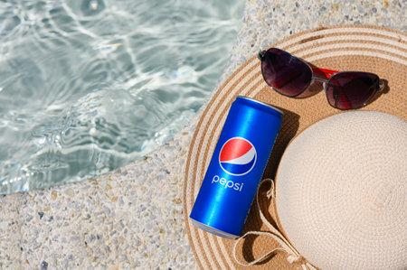 Novorossiysk - Russia, July 2022: Can of soft drink Pepsi Cola straw hat and sunglasses on the edge of the pool in the hotel. view from above.のeditorial素材