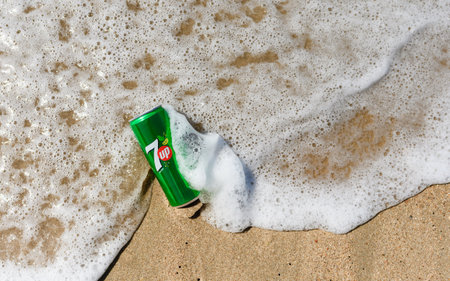 Anapa - Russia, July 2022: Can of soft drink 7 up in a sea wave on a sandy shore. view from above.のeditorial素材