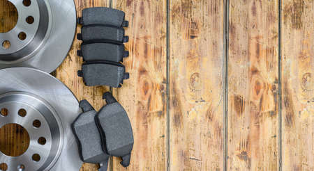 Set of new car spare parts on a wooden background. New brake discs and pads. top view, copy spaceの写真素材