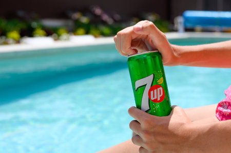Novorossiysk - Russia, July 2022: Girl opens a can of 7 up drink by the pool in the hotel. Close-up, selective focus on the logo.のeditorial素材