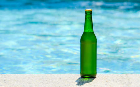 A bottle of cold light beer by the pool. Summer vacation concept. Horizontal format, copy space.の写真素材