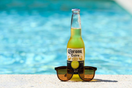 Novorossiysk - Russia, July 2022: Bottle of cold beer Corona Extra and sunglasses by the pool on a summer day.のeditorial素材