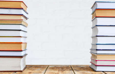 Two stacks of books on an old table against a brick wall. The space is empty in the center of the frame.の写真素材