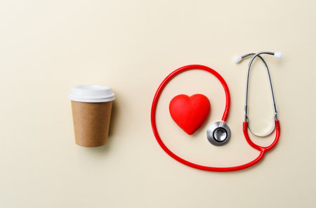 A cup for coffee and a phonendoscope with a heart. Concept of cardiovascular disease from frequent...