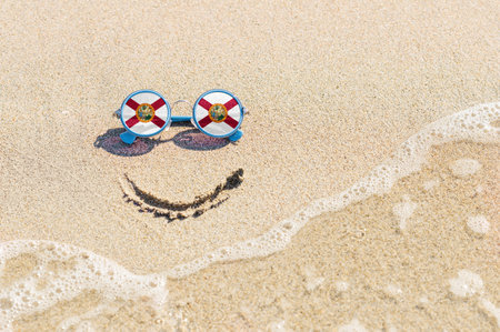 A painted smile on the beach and sunglasses with the Florida state flag. The concept of a positive holiday in the resort of Florida.の写真素材
