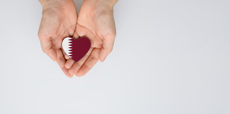 The national flag of Qatar in the shape of a heart in the hands. Flat lay, copy space.の写真素材