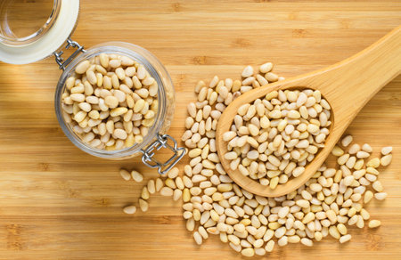 Pine nuts in a spoon next to a full jar of nuts. Healthy food concept. View from aboveの写真素材