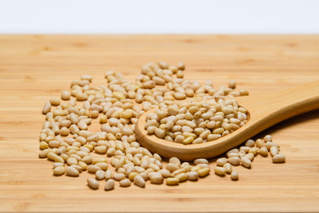 Pine nuts are scattered on a wooden table close-up.の写真素材