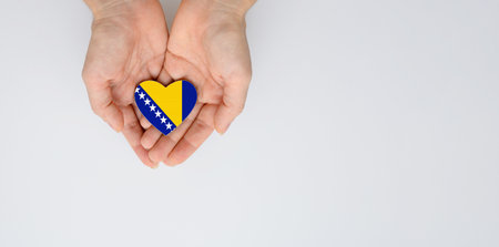The flag of the Bosnia and Herzegovina in the shape of a heart of arms in female hands. Flat lay, copy space.の写真素材