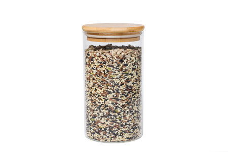 A mixture of various sunflower seeds in a glass jar on a white isolated backgroundの写真素材