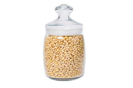 Glass jar with pine nuts on a white isolated backgroundの写真素材