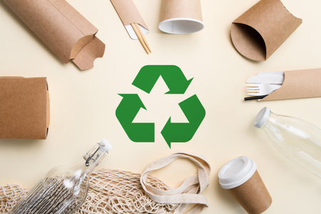 Eco-friendly items made from biodegradable materials lie around a green recycling sign. Waste recycling conceptの写真素材