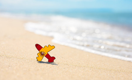 Vacation on the coast of Spain. Airplane in the colors of the flag of Spain on the seashoreの写真素材