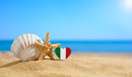 Beautiful beach in Italy. Flag of Italy in the shape of a heart and shells on a sandy beach.の写真素材