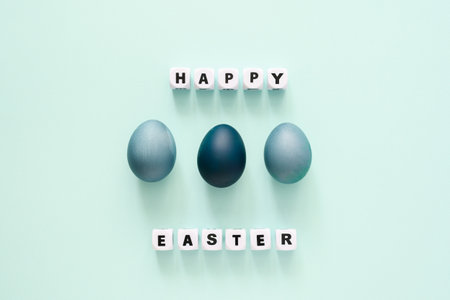 Easter greetings around blue painted eggs. flat layの写真素材
