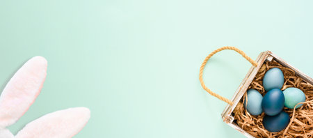 Wooden box with Easter eggs and rabbit ears on a blue background. copyspace.の写真素材