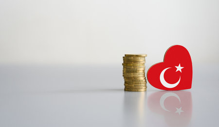 A stack of coins and the flag of Turkey in the shape of a heart. The concept of donations and financial assistance to Turkey.の写真素材