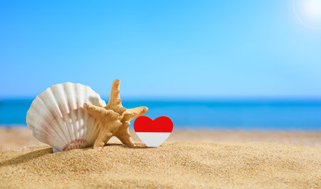 Beautiful Indonesian beach. Flag of Indonesia in the shape of a heart and shells on a sandy beach.の写真素材