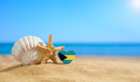 Beautiful beach in the Bahamas. Flag of Bahamas in the shape of a heart and shells on a sandy beach.の写真素材