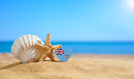 Beautiful beach in the Fiji. Flag of Fiji in the shape of a heart and shells on a sandy beach.の写真素材