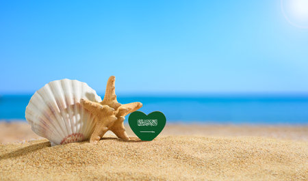 Beautiful beach in Saudi Arabia. Flag of Saudi Arabia in the shape of a heart and shells on a sandy beach.の写真素材