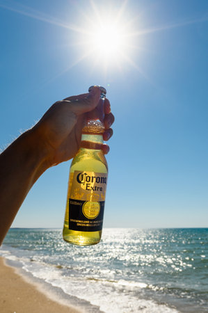 Anapa - Russia, August 2022: A bottle of Corona Extra beer against the backdrop of the bright sun and the seashore. Selective focus on the logo. vertical format.のeditorial素材
