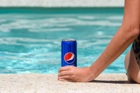 Novorossiysk - Russia, July 2022: A young girl is sitting by the pool with a can of cold Pepsi Cola. summer vacation conceptのeditorial素材