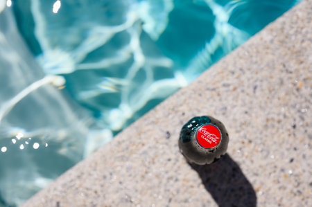 Novorossiysk - Russia, July 2022: A bottle of Coca Cola stands by the pool on a hot day. Close-up, selective focus on the lid with the logo.のeditorial素材
