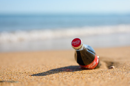 Anapa - Russia, July 2022: A bottle of Coca Cola on the evening beach. Recreational concept. Selective focus on the lid with logo.のeditorial素材